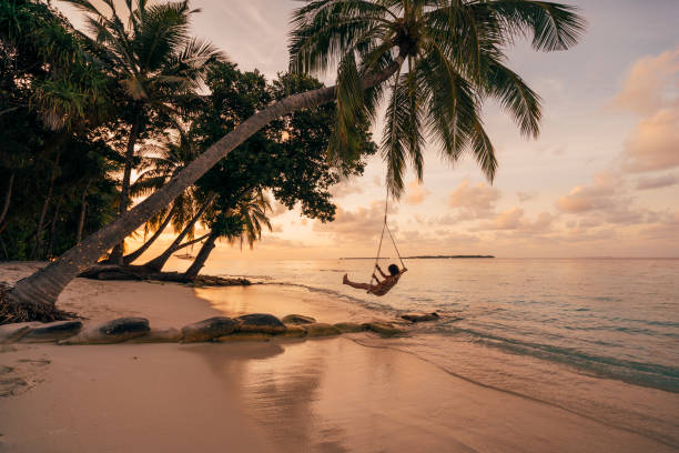 joven mujer adulta relajándose en un columpio en un paraíso tropical - travel destinations fotos fotografías e imágenes de stock