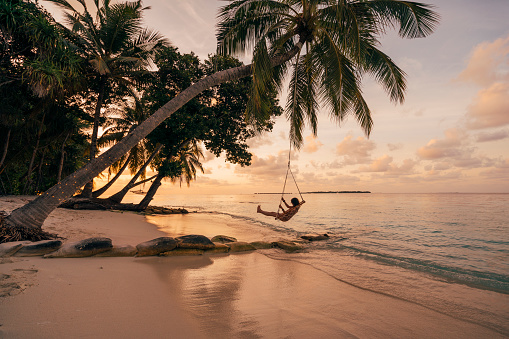 Young adult woman relaxing on a swing in a tropical paradise