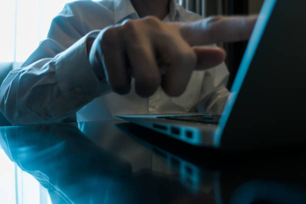 Laptop and wireless mouse placed on an orange desk with dramatic lighting from blinds, creating a stylish and minimal office mood.