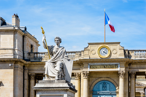 Close-up view of the statue named The Law at the center of the place du Palais Bourbon with the entrance of the Palais Bourbon in the background, seat of the French National Assembly in Paris, France.
