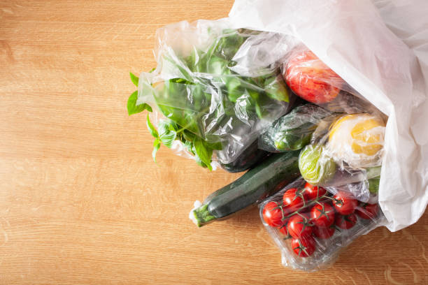 single use plastic packaging issue. fruits and vegetables in plastic bags - pacote plastico imagens e fotografias de stock