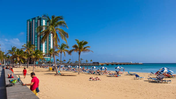 Tourists relaxing on the Playa de El Reducto, the large beach of Arrecife, the capital city of Lanzarote, located in the centre-east of the island.