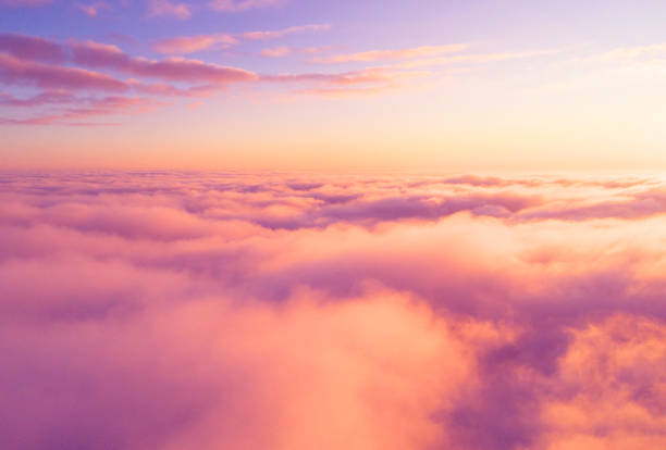 Photo of Aerial view White clouds in blue sky. Top view. View from drone. Aerial bird's eye view. Aerial top view cloudscape. Texture of clouds. View from above. Sunrise or sunset over clouds