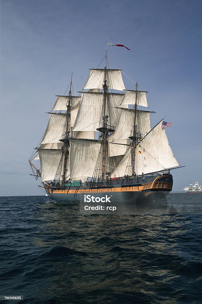 Pirate ship sailing at sea under full sail Vintage frigate Sailing Ship at Sea under full sail with tall ships in the background. Pirate - Criminal Stock Photo