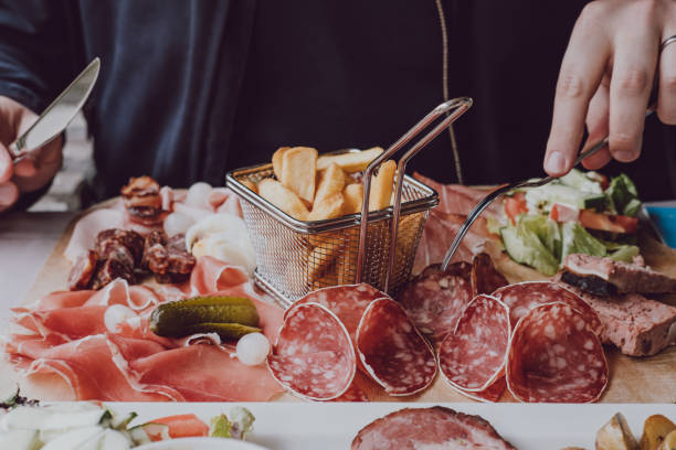 istock Male hands holding a fork over cold meats platter, selective focus. 1161406469