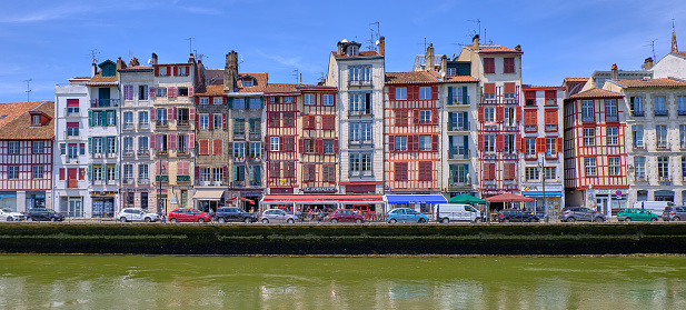 Bayonne, France June 8 2019: View of typical basque architecture on houses along the Nive river.  Straight view from across.