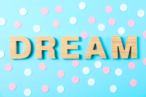 istock Word Dream lined with wooden letters on color background with glitter 1161406809