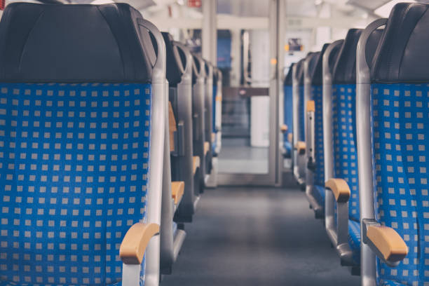 Rows of seats on an empty modern train, travel concept, selective focus. Rows of blue fabric seats with leather headrests on both sides of an aisle inside empty modern train, travel concept, selective focus. emergency exit photos stock pictures, royalty-free photos & images