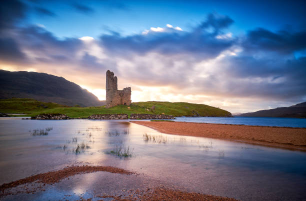 ruinen der burg ardvreck am ufer des loch assynt bei sonnenuntergang, sutherland, highlands of scotland. - highlands region loch reflection mountain stock-fotos und bilder