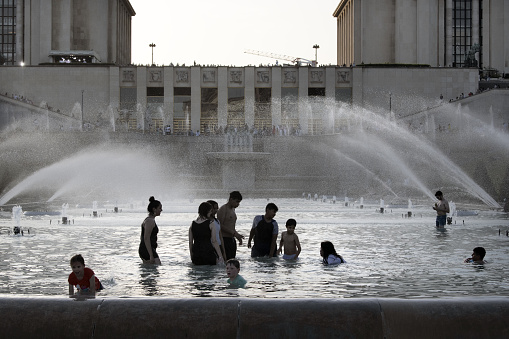 Europe, France, Paris, 2019-06, The Trocadero gardins a popular touristic attraction facing the Eiffel Tower shows people bathing in the fountains in an effort to cool down during the heatwave.