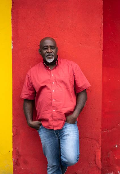 istock Mature man in jeans and shirt leaning back on red wall 1161409430