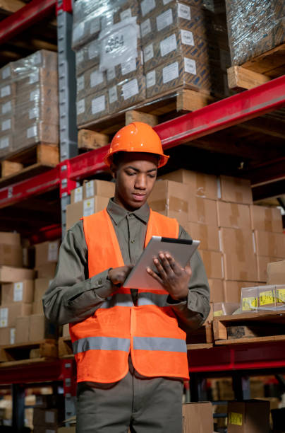 istock Young black man working at a warehouse looking at tablet wearing protective workwear 1161410951