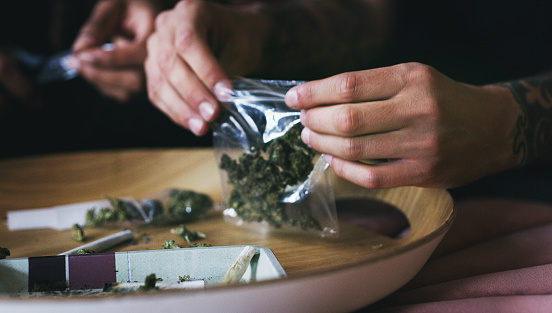 Cropped shot of a man rolling a marijuana joint at home