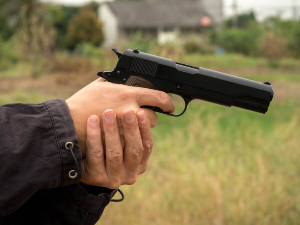 istock Killer holding a gun, Hand holding guns isolated on white background. 1161412060