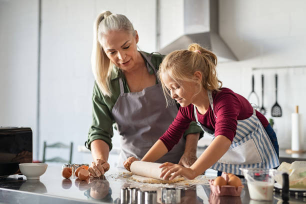 おばあちゃんと生地を転がす小さな女の子 - grandmother pie cooking baking ストックフォトと画像