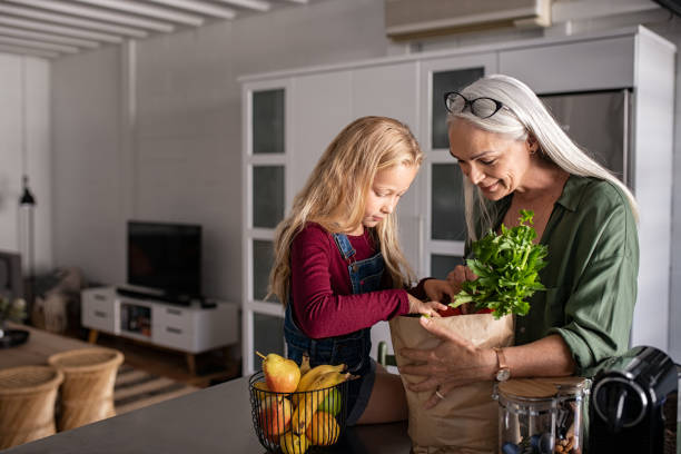 oma und mädchen halten lebensmittel-einkaufstasche - child eating healthy eating healthy lifestyle stock-fotos und bilder