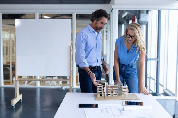 istock Male and female architect discussing over architectural model at table in a modern office 1161412645
