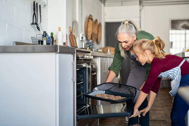 cooking cookies in the oven - grandmother cooking baking family imagens e fotografias de stock