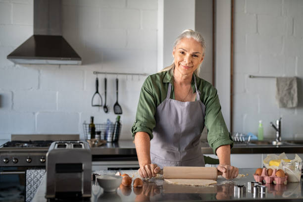 Happy senior woman rolling dough