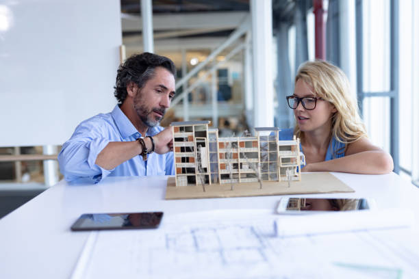 istock Male and female architect discussing over architectural model at table in a modern office 1161412704