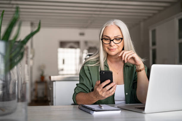 elegante mujer senior mensajería con teléfono - mujeres mayores fotografías e imágenes de stock