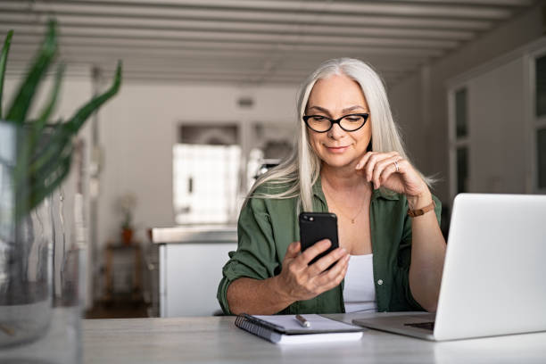 stylowa wiadomość dla starszej kobiety z telefonem - biała kobieta czyta w okularach zdjęcia i obrazy z banku zdjęć