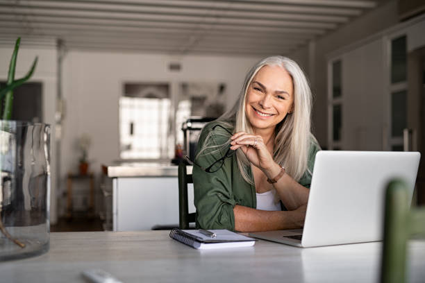 Happy senior fashionable woman Portrait of happy senior woman holding eyeglasses and looking at camera at home. Successful old lady laughing and working at home. Beautiful stylish elderly woman smiling and relaxing at home. carefree senior stock pictures, royalty-free photos & images