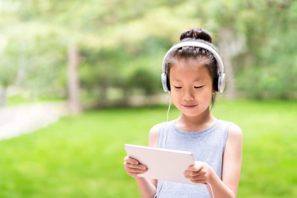 istock A cute asian little girl using digital tablet in public park 1161416500
