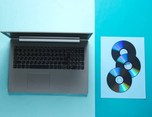istock Modern laptop and many CDs on a blue background. 1161418148