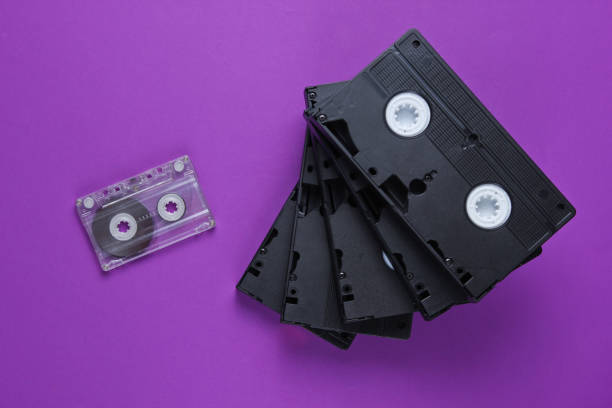 istock Stack of retro video and audio cassettes on purple background. Top view 1161421497