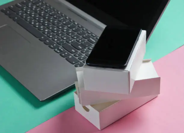 Photo of The concept of unboxing, techno blogging. Box with a new smartphone, laptop on pastel background.