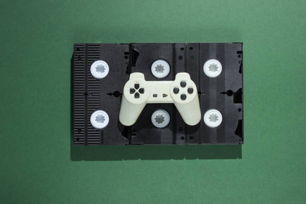 istock Gamepad on retro video cassettes. Minimalism studio shot on green background 1161421792