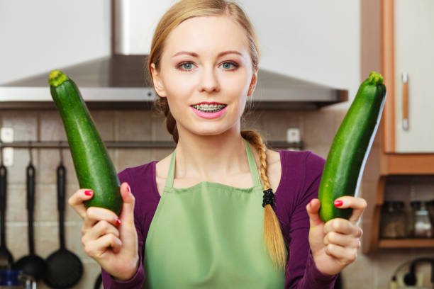 istock Woman in kitchen holds zucchini vegetable 1161421862