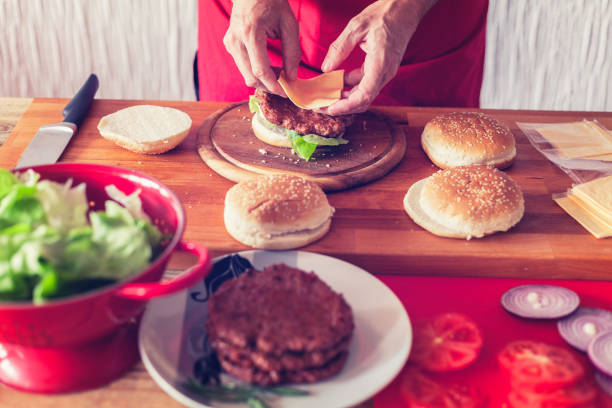 istock Hamburger preparing, sheet of soft cheese put on burger bun, close-up 1161422724