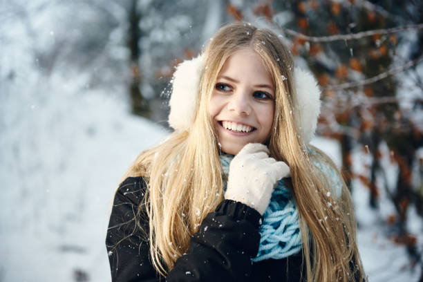 зимний портрет улыбающейся красивой блондинки с белыми муфтами уха и перчатками под снегом. - white denmark nordic countries winter стоковые фото и изображения
