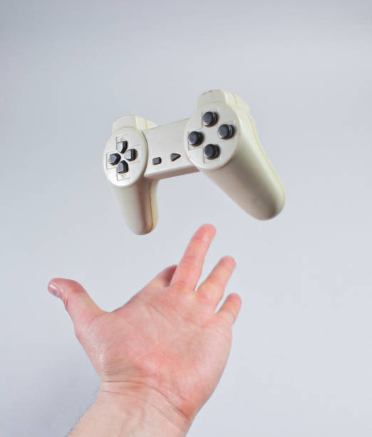 Male hand throwing up a gamepad on a gray background.