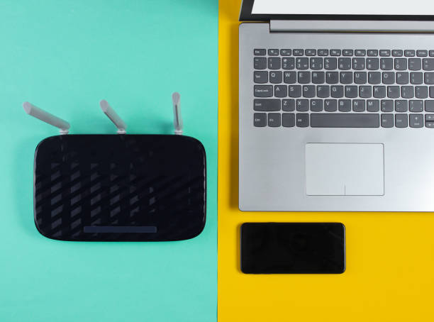 istock Wi fi router, smartphone, laptop on  colored background. Modern gadgets. Top view 1161429406