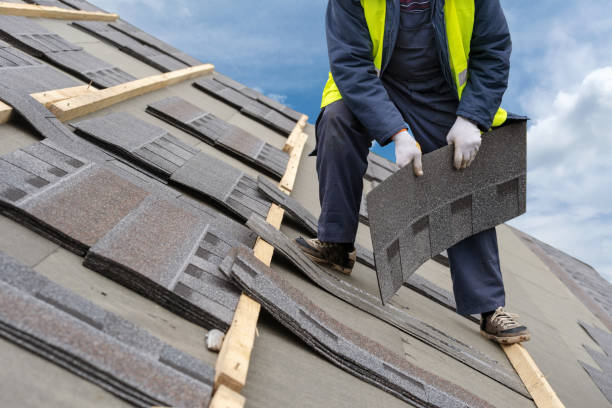 istock Qualified roofer worker in uniform work wear holding in hands and installing asphalt or bitumen tile on top of the roof under construction house against beautiful blue sky on background 1161429553