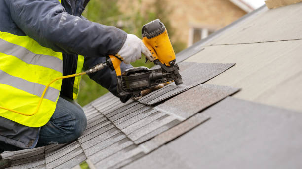 istock Unrecognizable roofer worker in special protective work wear and gloves, using air or pneumatic nail gun and installing asphalt or bitumen shingle on top of the new roof under construction residential building 1161429641