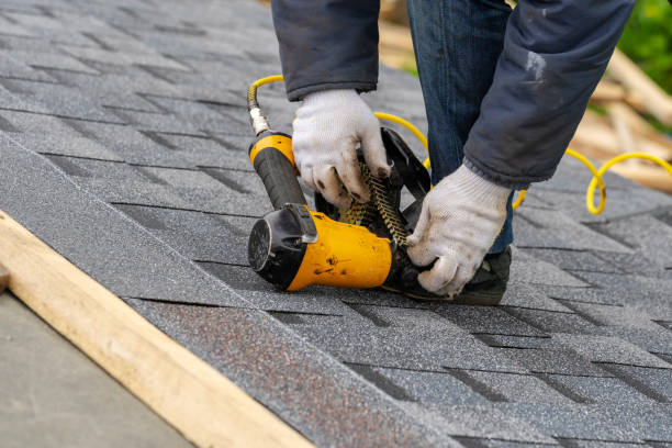 istock Close up and real photo of professional workman in protective uniform using air or pneumatic nail gun and installing asphalt or bitumen tile on top of the roof under construction house 1161429651