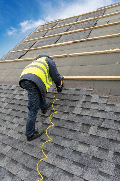 istock Vertical photo of unrecognizable roofer worker in uniform work wear using air or pneumatic nail gun and installing asphalt or bitumen tile on top of the roof under construction house 1161429659