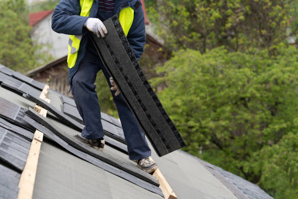 istock Mature and skilled workman in special protective work wear installing asphalt or bitumen shingle on top of the new roof under construction residential building 1161429664