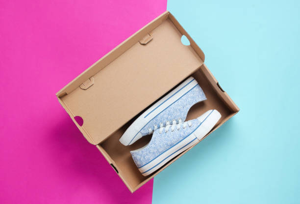 istock New trendy sneakers in cardboard box on colored background. Top view 1161430946