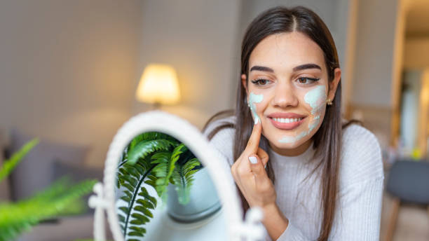Natural homemade facial masks at home. Natural homemade facial masks at home. Woman applying mask on her face and looking in the mirror. Beautiful woman applying natural facial mask. Beauty treatments. facial mask beauty product stock pictures, royalty-free photos & images