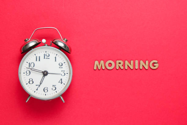 istock Retro alarm clock on red background with text morning with letters. 1161431313
