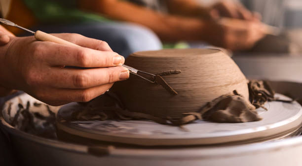istock Pottery maker trimming molded clay on a pottery wheel 1161431321