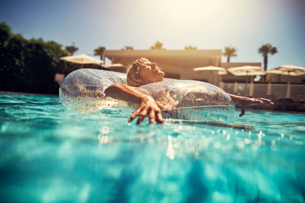 szczęśliwa starsza kobieta ciesząc się basenem - floating on water women swimming pool water zdjęcia i obrazy z banku zdjęć