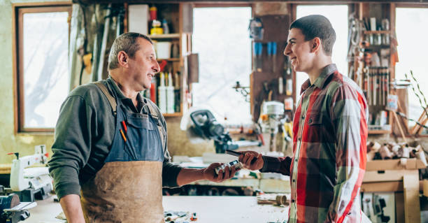 istock Man at wood workshop paying contactless with smartphone 1161433373