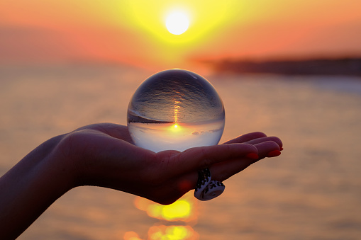 Crystal ball in the palm with an inverted reflection of the sunset on the sea in Turkey in Kizilagac near Side and Antalya.