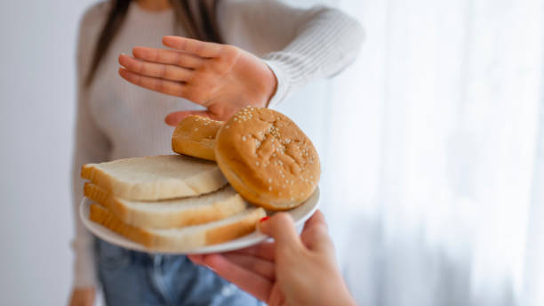 молодая женщина на безглютеновой диете говорит нет благодаря тост - dieting food rejection women стоковые фото и изображения